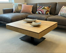 Laden Sie das Bild in den Galerie-Viewer, Höhenverstellbarer Couchtisch Ronald Schmitt Lignum K472 mit offener Ablage und verschiebbarer Schublade aus massiver gerillter Eiche, inszeniert in moderner Wohnzimmerumgebung.