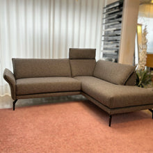 Laden Sie das Bild in den Galerie-Viewer, Modernes Ecksofa Violetta Modell Tilda in grauer Stoffausführung auf rosa Teppich – Ausstellungsstück im Möbelhaus Zeppenfeld in Olpe.