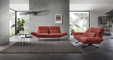 Laden Sie das Bild in den Galerie-Viewer, Relaxsofa Meda von Nolte Polster in Amarena-Rot mit individuell verstellbaren Armlehnen – modernes Design in offenem, lichtdurchflutetem Wohnraum mit Betonwand und großen Fensterfronten.