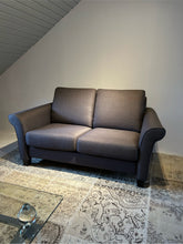 Laden Sie das Bild in den Galerie-Viewer, Frontansicht des Schröno Sofa Individual in braunviolettem JAB Anstoetz Stoff Vito 55 auf Teppich mit Glas-Couchtisch