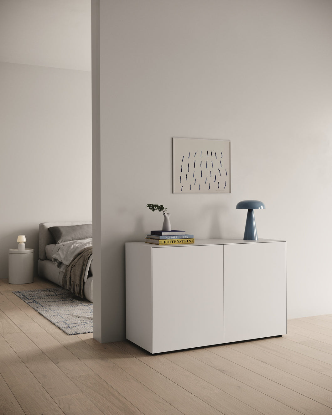 Kompakte Nex Pur Box mit zwei Türen in Weiß, freistehend vor einer Wand zwischen Schlafzimmer und Flur, mit Deko und Designlampe, auf hellem Holzfußboden – moderner, luftiger Look.