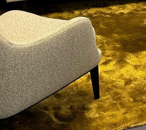 BW Sessel Grace niedrig in Stoff Mara 575 – einzeln arrangiert vor Wohnwand mit Designteppich in Ausstellungsambiente
