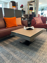 Laden Sie das Bild in den Galerie-Viewer, Moderner Ronald Schmitt Janas K 471 Couchtisch mit verschiebbarer Schublade und grauer Keramikplatte, präsentiert im Showroom von Zeppenfeld Wohn Evolution in Olpe in der Ausstellungsumgebung

