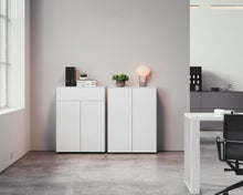 Laden Sie das Bild in den Galerie-Viewer, Zwei nebeneinander platzierte Kommoden Piure Nex Pur Box 2041100 und 2041300 in edlem Mattweiß, perfekt integriert in ein modernes Büroambiente mit minimalistischem Look
