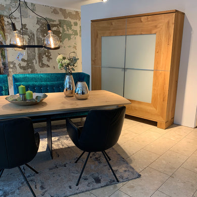 Großer Schrank Varus von Scholtissek in knorriger Eiche mit Glasfront in Sand matt – inszeniert im Essbereich mit Designmöbeln